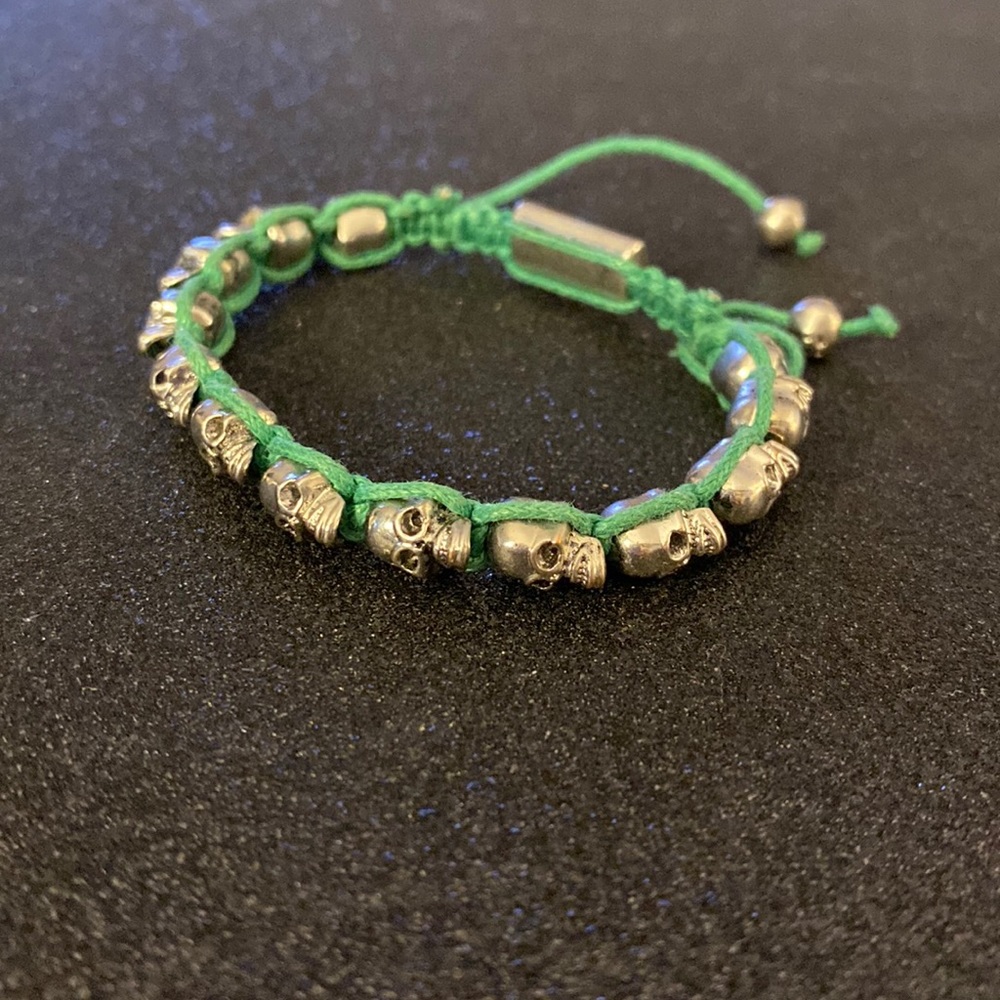 Bracelet w green yarn and silver skull heads